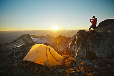 A hiker takes a picture of his tent while camping on Saxifrage Peak, Pemberton, BC, Canada.