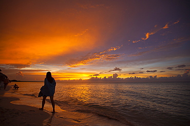 A silhouetted young woman wrapped in a towel walks the beach just after sunset in Cayo Coco, Cuba.