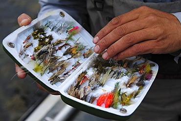 A fly fisherman examines his fly box.