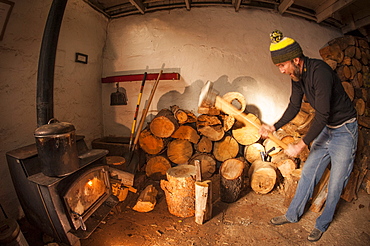 Man splitting firewood inside the Peter Grubb Hut, Sierra Nevada