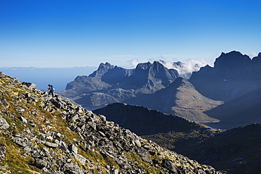 Female hiker ascending a rocky ridge on Branntuva (702m), Moskenesøy, Lofoten Islands, Norway