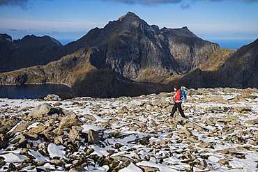 Female hiker on the rocky summit of Munken after a light autumn snow, Moskenesøy, Lofoten Islands, Norway