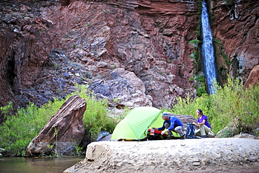 Hikers setup camp on a beach along the Colorado River near the plumeting 180-foot Deer Creek Falls in the Grand Canyon outside of Fredonia, Arizona November 2011.  The 21.4-mile loop starts at the Bill Hall trailhead on the North Rim and descends 2000-feet in 2.5-miles through Coconino Sandstone to the level Esplanada then descends further into the lower canyon through a break in the 400-foot-tall Redwall to access Surprise Valley.  Hikers connect Thunder River and Tapeats Creek to a route along the Colorado River and climb out Deer Creek.