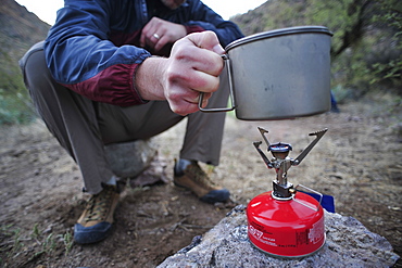 Woman and man backpackers prepare dinner with a camp stove at camp close to Charleboise Springs in La Barge Canyon on the Dutchmans Trail in the Superstition Wilderness Area, Tonto National Forest near Phoenix, Arizona November 2011.  The trail links up with the popular Peralta Trail and offers a spectacular tour through the rugged Sonoran desert.