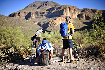 Man and woman backpackers hike on the Dutchmans Trail in the Superstition Wilderness Area, Tonto National Forest near Phoenix, Arizona November 2011.  The trail links up with the popular Peralta Trail and offers a spectacular tour through the rugged Sonoran desert.