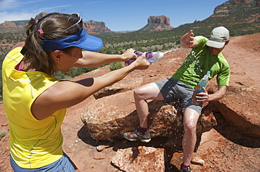 Couple plays with water bottles the Cathedral Rock Trail in Sedona, Arizona. The trail over slick rock sandstone leads to a popular group of spires above Sedona.