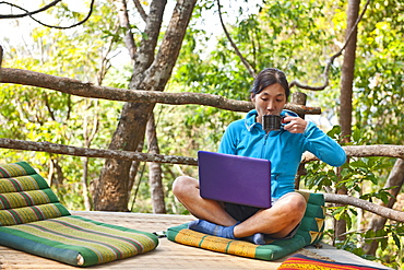 Woman sitting with her laptop on an outdoor terrase at a street cafe in northern Thailand