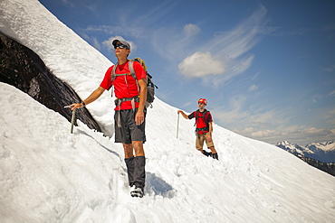 Two climber cross a snowfield high in the mountains of British Columbia, Canada.