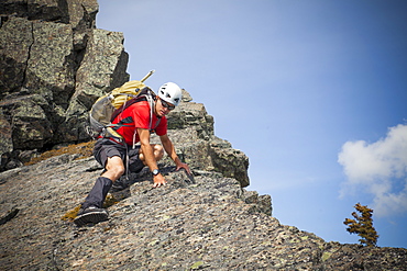 A climber carefully down climbs a rocky summit in British Columbia, Canada.