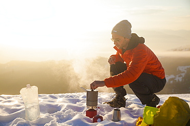 A climber attends to his boiling water on a camping stove while camping in the mountains of British Columbia, Canada.