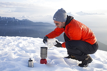 A climber pours water into a camping stove while camping in the mountains of British Columbia, Canada.