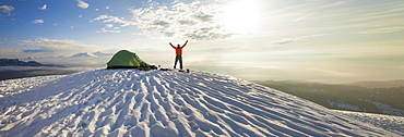 A climber poses beside his tent the morning after camping on the snow in the mountains of British Columbia, Canada.