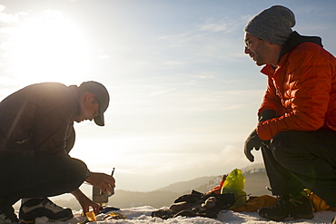 Two climbers converse while  cooking breakfast in the mountains of British Columbia, Canada.