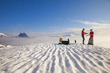 Two climbers pack up their tent after camping on the snow in the mountains of British Columbia, Canada.