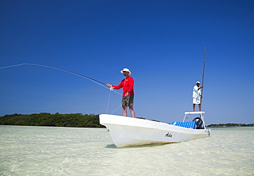 A man fly fishes in the clear waters off the coast of Belize, Belize