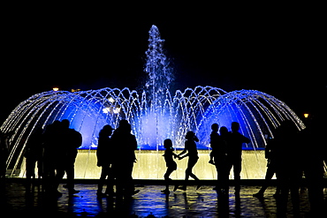 Visitors are silhouetted by a lit-up fountain at Reserva Park in Lima, Peru.