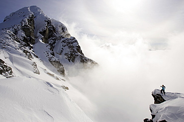 Dan Treadway looking out over winter clouds and mountains on skis in Knights Inlet, British Colombia, Canada, April 7th 2007, Canada