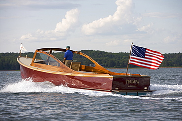 Senior man drives a power yacht in Somes Sound, Maine, United States of America