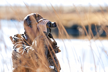 Brad Jackson uses binoculars scans the area for ducks in Carson City, NV, United States of America