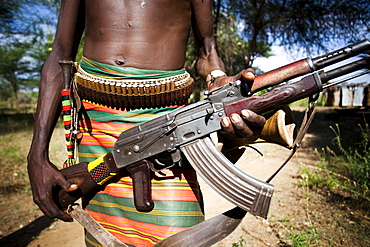 HAMER VILLAGE, OMO VALLEY, ETHIOPIA. An Ethiopian man holds a kalashnikov rifle at his waist, Ethiopia