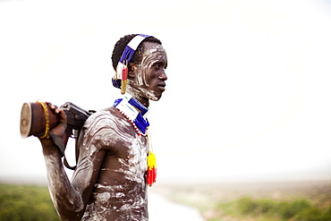 KARO VILLAGE, OMO VALLEY, ETHIOPIA. A young man holds his kalashnikov rifle while overlooking the Omo river in the remote Omo Valley of Ethiopia. (released: MHP_095_MR_RedKere), Ethiopia