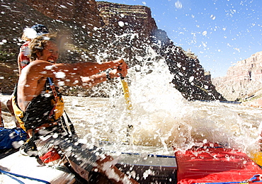 Raft guide, Marcus Cline gets splashed as he guieds his raft through the rapids of Cataract Canyon in Canyonlands National Park, Utah, United States of America