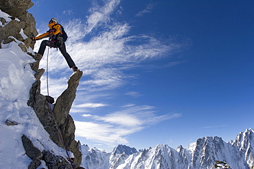 A mountain climber steps across peaks during his ascent of Alpinisme - Aiguille d'Argentiere, France