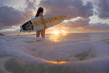 A young woman enters the surf at sunrise. Blueys Beach, Australia, Australia