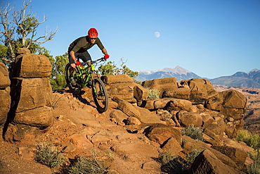 Man mountain biking on a trail in a desert environment.