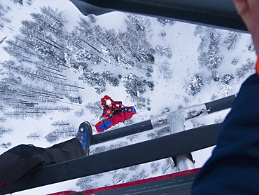 An emergency doctor is together with a patient being hosted up to a rescue helicopter in the Swiss Alps.