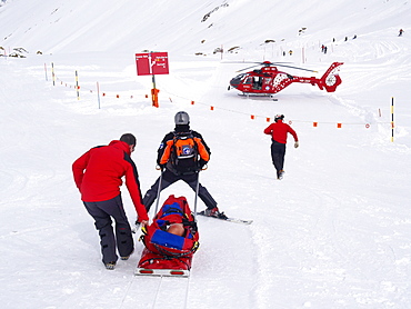 Rescue Personnel is helping an injured skier in the ski area of Zermatt in the Swiss Alps.