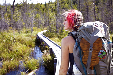 A hiker crosses a foot bridge in the Swamps of Maine.