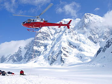 Mountain Ranger waiting to be picked up by a  helicopter in Denali National Park, Alaska. Mount Hunter is in the background.