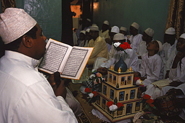 A Swahili man reads from the Koran at a gathering of men in a house in Lamu to celebrate Maulidi, the birthday of the Prophet. Lamu Island, Kenya