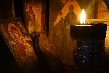 Icons and a lit candle inside a roadside, religious shrine. Crete. Greece