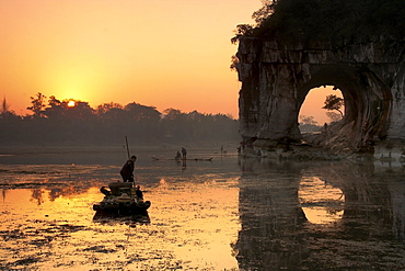 Chinese fisherman on a bamboo raft in Li Jang River, Yangshuo, Guilin, Guangxi region, China.