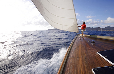 A man stands on the bow of a yacht while sailing near St. Bartholomew, French West Indies.