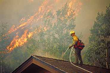 Fire fighter protects home from fire.