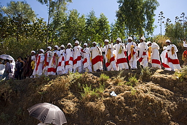 Group of priests dressed in ceremonial clothes chanting and dancing in procession during Timkat festival in Lalibela, Ethiopia