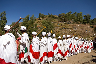 Group of priests dressed in ceremonial clothes chanting and dancing in procession during Timkat festival in Lalibela, Ethiopia