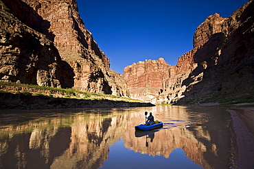 A person paddling an inflatable kayak duckie down the Colorado river, Utah.