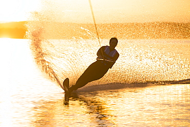 A woman water skis on Whitefish Lake at sunset in Whitefish, Montana.