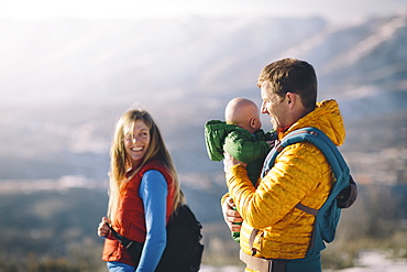 A young couple and their baby hike in the wintry mountains.
