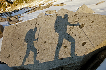 The shadows of two backpackers on a large rock.