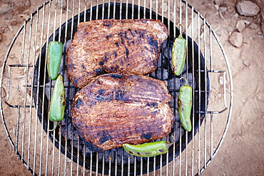 Steak and pepers cookin on a grill.