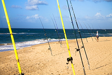 A man tends to his fishing rod on the beach.