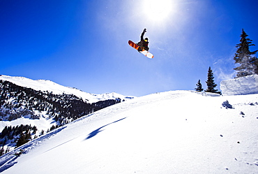 A man hits a backcountry jump on his snowboard on Red Mountain Pass in Southwest Colorado.