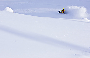 A man slashes deep snow on his snowboard and creates a large powder cloud in Utah's Wasatch mountains.