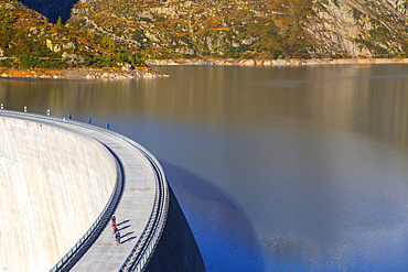 Four road bikers on the dam of the Emosson reservoir lake in the Alps on the border of France and Switzerland. It is an early morning training session of the local cyclists. The climb from Martigny to Finhaut will be stage 17 of the 2016 Tour de France on July 20th 2016. Depart is in Bern and the finish near the Emosson reservoir, Lac d'Emosson, at 1960 meters height.