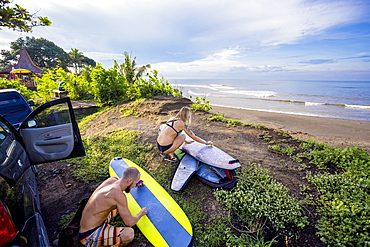 Young surfers are waxing their boards before surf session, Balian village, Bali, Indonesia